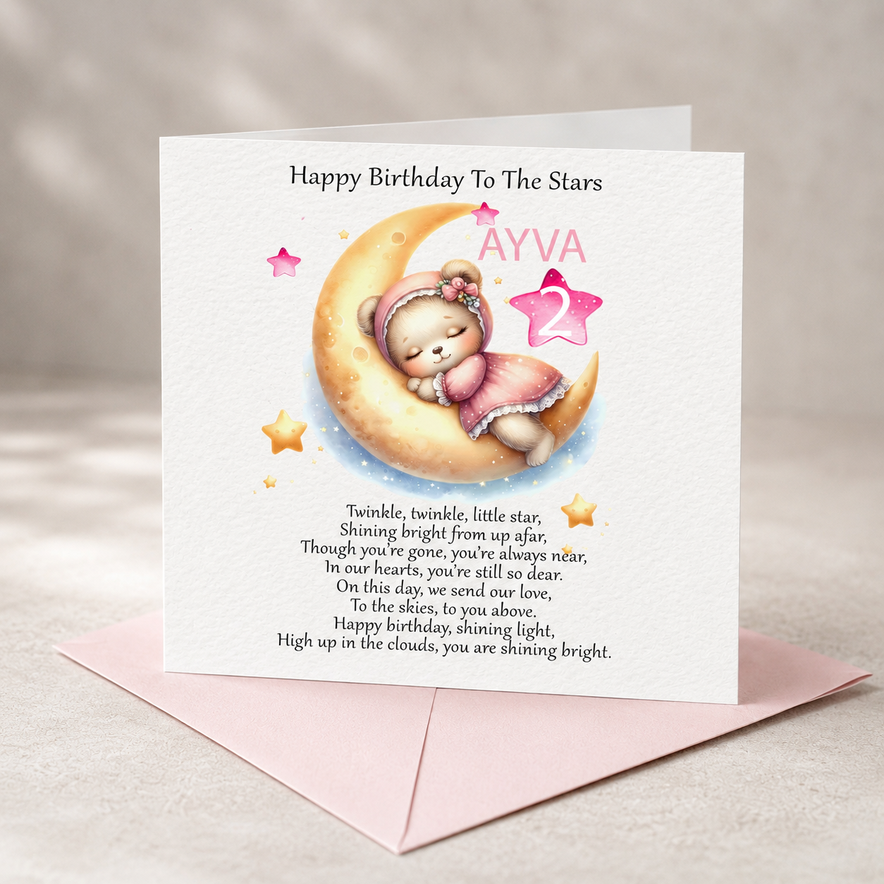 appy Birthday To The Stars memorial card featuring a sleeping bear on a crescent moon, displayed on white hammered cardstock with a soft pink envelope.