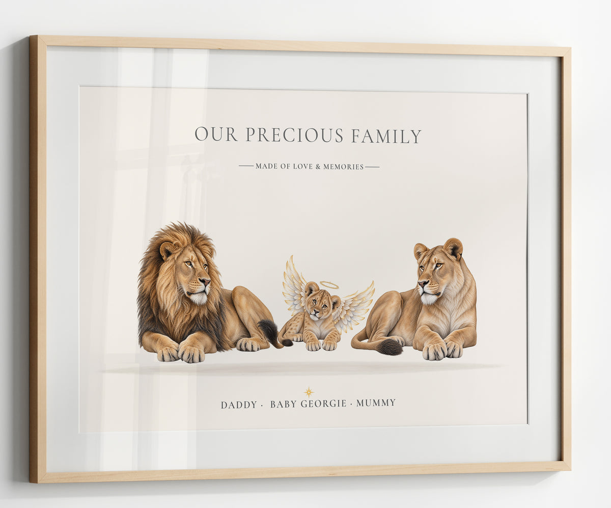 A personalized framed art print featuring an illustration of a lion, a lioness, and a baby lion with angel wings. The print has a cream background with elegant black text reading 'OUR PRECIOUS FAMILY' and 'DADDY - BABY GEORGIE - MUMMY'.