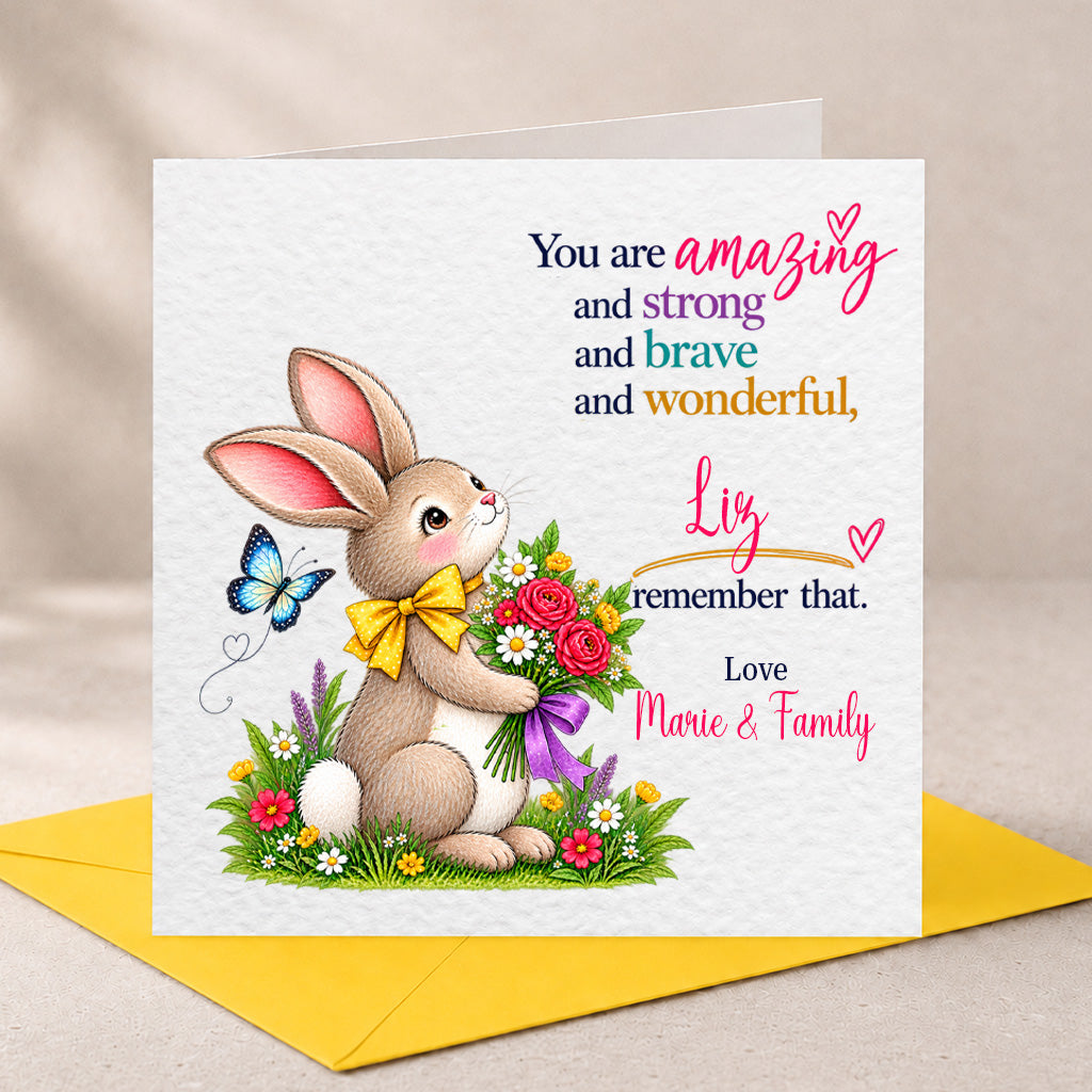 A square Easter greeting card with a white textured background, featuring an illustrated brown bunny holding a bouquet of red, pink, and white flowers with a yellow bow. The card has personalized text in black, pink, blue, and orange.