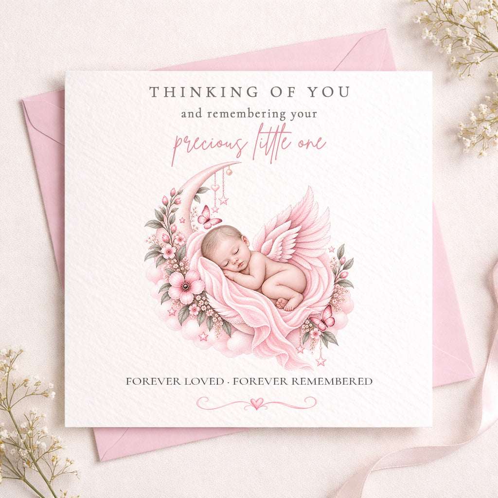 A square white memorial card with a pink and gray illustration of a sleeping baby angel on a crescent moon, surrounded by flowers. The card reads 'THINKING OF YOU and remembering your precious little one' and 'FOREVER LOVED - FOREVER REMEMBERED'.