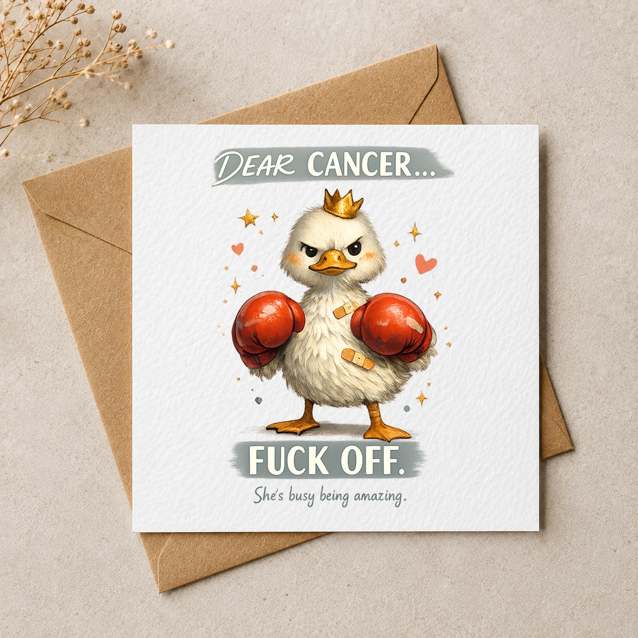 A square greeting card with a brown kraft envelope behind it, featuring an illustrated white chick wearing red boxing gloves and a small gold crown, with the text 'DEAR CANCER.