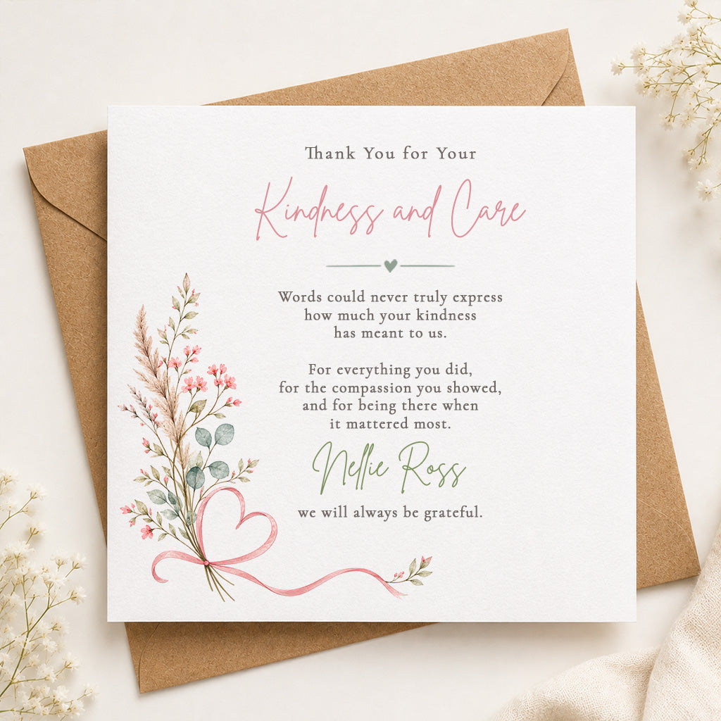 A square white thank-you card with elegant pink and green text and floral illustrations, placed on top of a brown kraft envelope with dried flowers around it.
