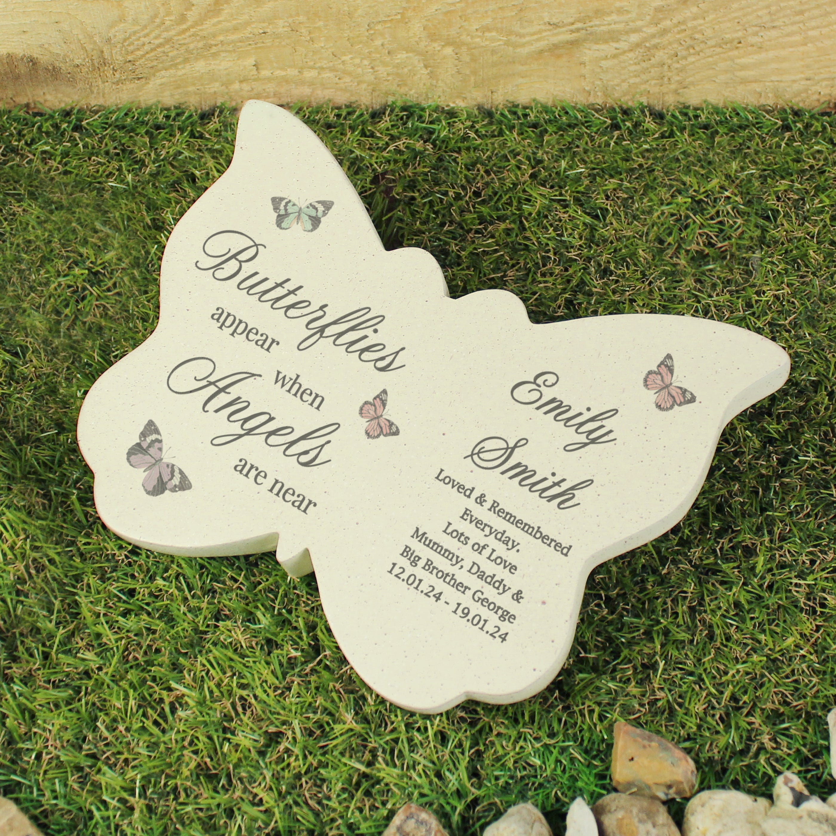 Butterfly-shaped memorial plaque with engraved text on a grassy background