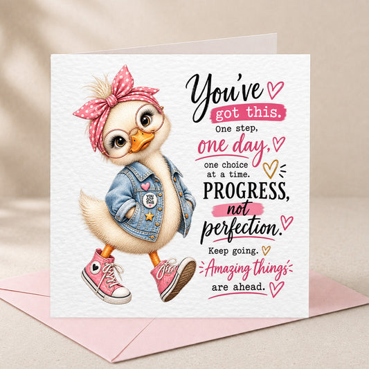 A square greeting card with a white textured background, featuring a cute cartoon duck wearing a pink polka-dot bow headband, denim jacket, and pink sneakers, alongside motivational text. The card is displayed on a light pink envelope against a soft beige fabric backdrop.