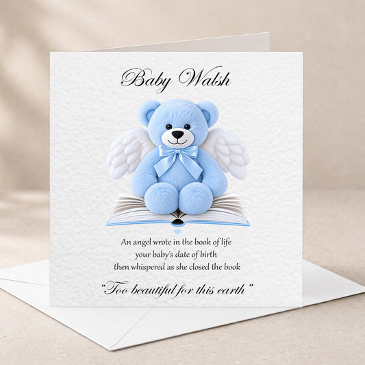 A square white baby memorial card with a blue teddy bear with white angel wings sitting on an open book. The card is personalized with the name 'Baby Walsh' at the top and a memorial poem below.